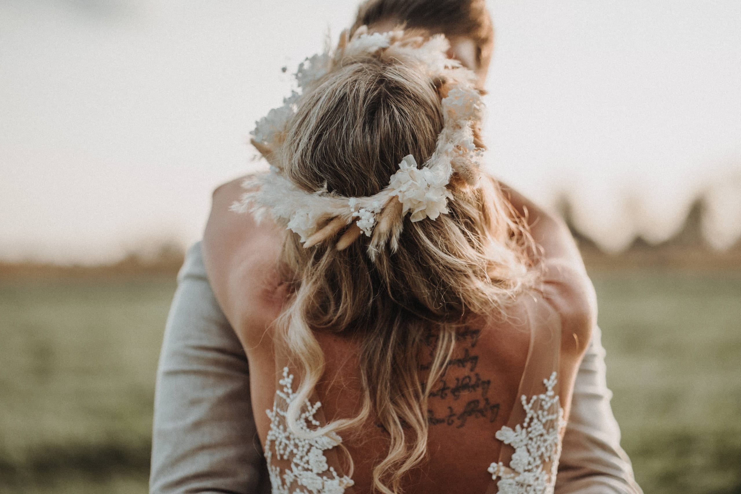 Die Braut mit Blumenkranz von hinten in den Armen des Bräutigams